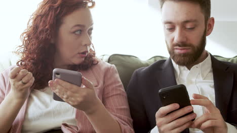 Woman-And-Man-In-Formal-Wear-Using-Mobile-Phone-And-Talking-Together-While-Sitting-On-Sofa-2