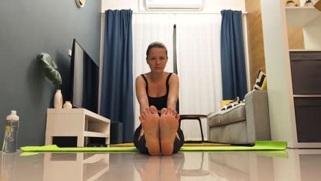 mujer haciendo estiramientos de yoga en casa