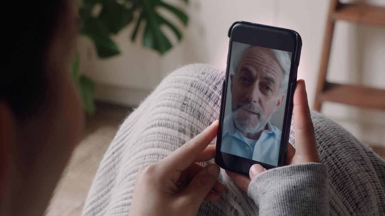 mujer joven teniendo video chat usando teléfono inteligente en casa hablando con el abuelo mostrando el estilo de vida de compartir apartamento disfrutando de la comunicación por teléfono móvil