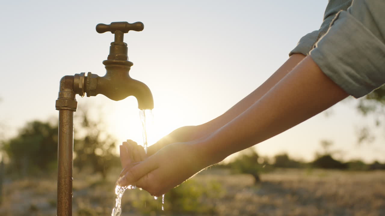 manos de una mujer atrapando agua bajo el grifo un granjero sediento bebiendo agua dulce que fluye del grifo al atardecer concepto de ahorro de agua