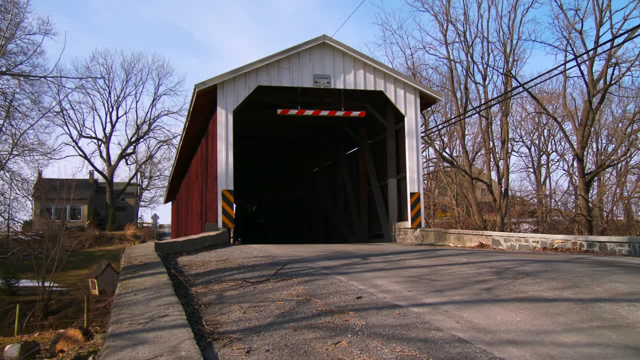 아미쉬 마차는 시골 펜실베이니아 2의 도로를 따라 덮힌 다리를 통과합니다.