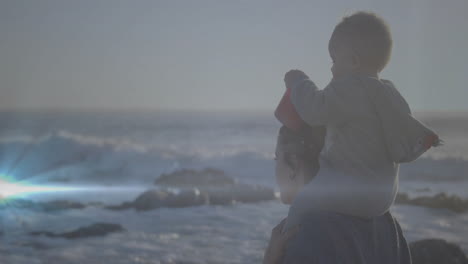 walking on beach, mother carrying child on shoulders, both enjoying animation