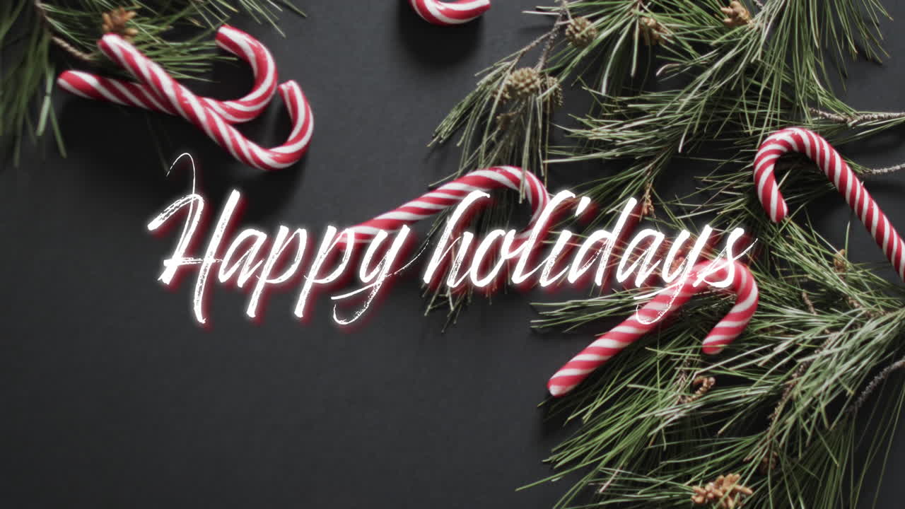 Happy holidays text in white over christmas tree sprigs and candy canes on black