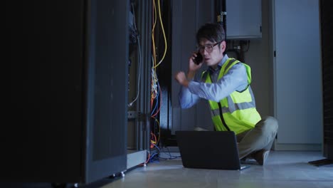 técnico informático asiático que usa un teléfono inteligente y una computadora portátil comprobando el servidor de la computadora