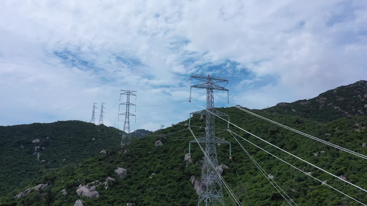 Aerial drone footage of high voltage power transmission towers with line pylon in mountainous area to distribute electricity - Natural landscape and industrial concept for sustainable development