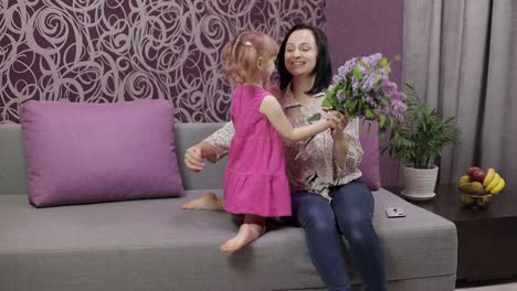 Little-daughter-child-congratulates-mother-with-bouquet-of-flowers.-Slow-motion