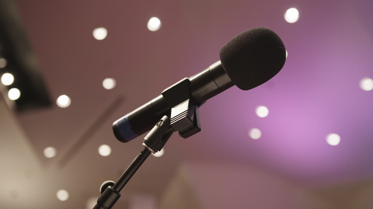 Wide shot of a peaceful, non-denominational church sanctuary or school auditorium with a microphone on a stand—capturing the quiet ambiance of a neutral, multipurpose space ready for gathering.