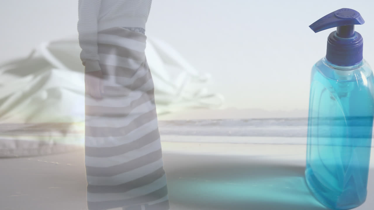 해변에 있는 여성에 대한 얼굴 마스크와 위생제 병의 디지털 복합 비디오