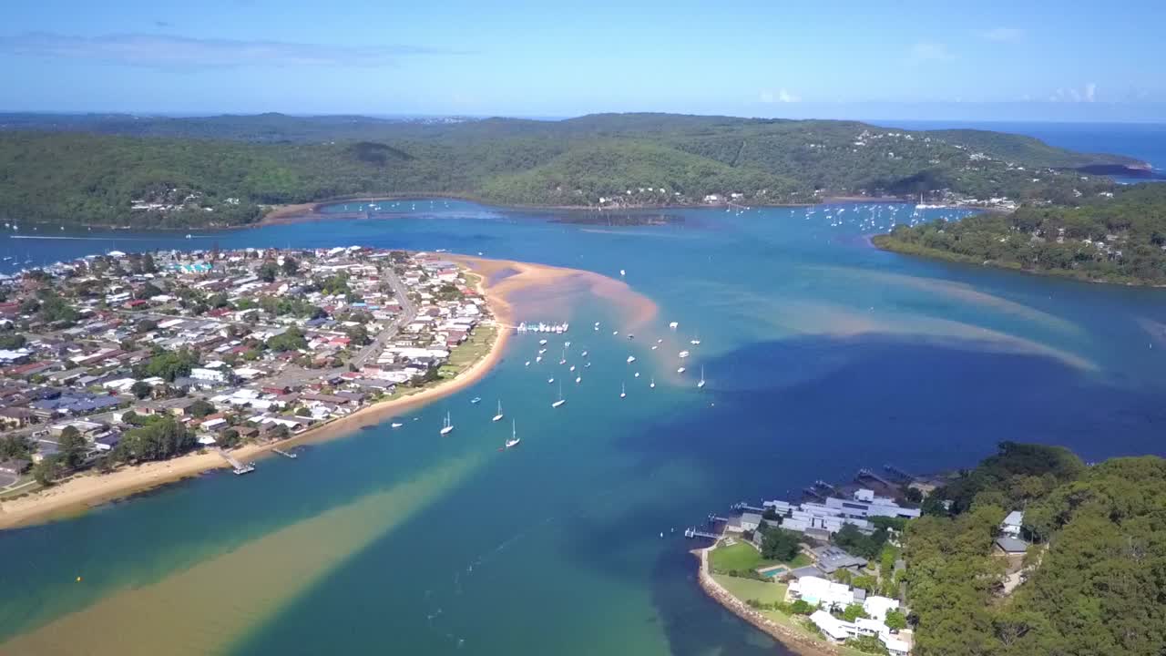 Stunning view of turquoise water beach, lagoon and houses with national park forest at the distance. Reverse aerial shot.