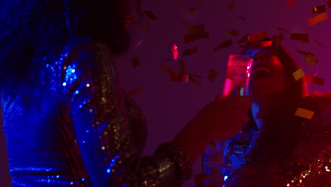 cerca de dos mujeres en un bar de club nocturno o discoteca bailando y bebiendo alcohol con confeti de papel 2