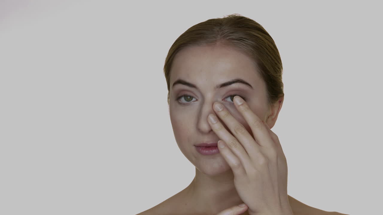 bella mujer rubia arreglándose las líneas de los ojos y las cejas como maqueta de cuidado facial