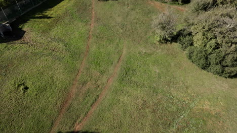 mountain bikers ride along a dirt trail through a grassy field