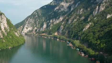 Wooden-Houses-Floating-On-Lake-Perucac-Surrounded-With-Lush-Vegetation---aerial-drone-shot