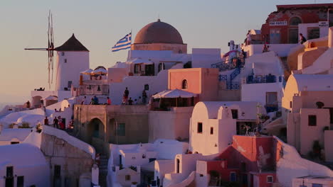 edificios blancos y molinos de viento bordean las laderas de la isla griega de santorini al atardecer 3