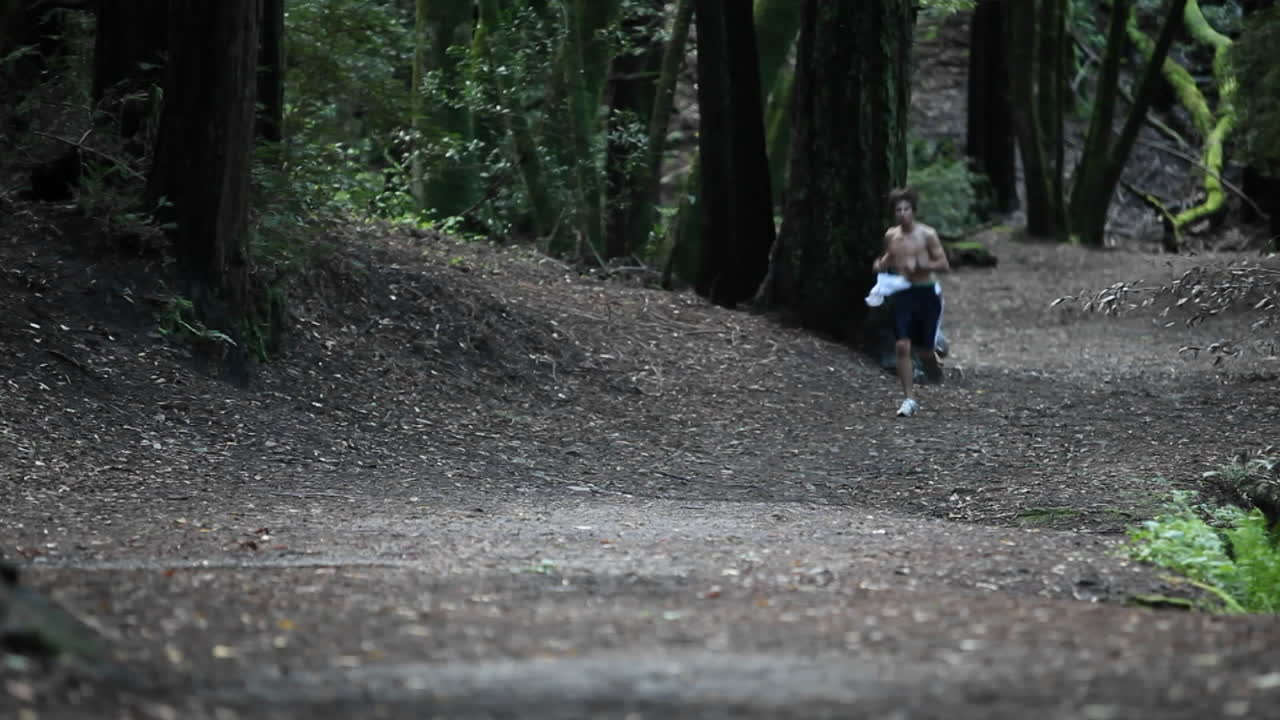 벗은 남자가 숲이 우거진 지역에서 실행