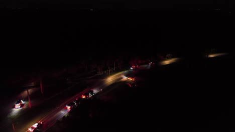 flashing red lights of medical cars at night. aerial flyover shot. highway intersection with fire trucks and ambulance vehicles during fire operation. american city suburb in florida, united states.