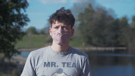 young man puts on homemade flower pattern corona virus cotton mask medium shot