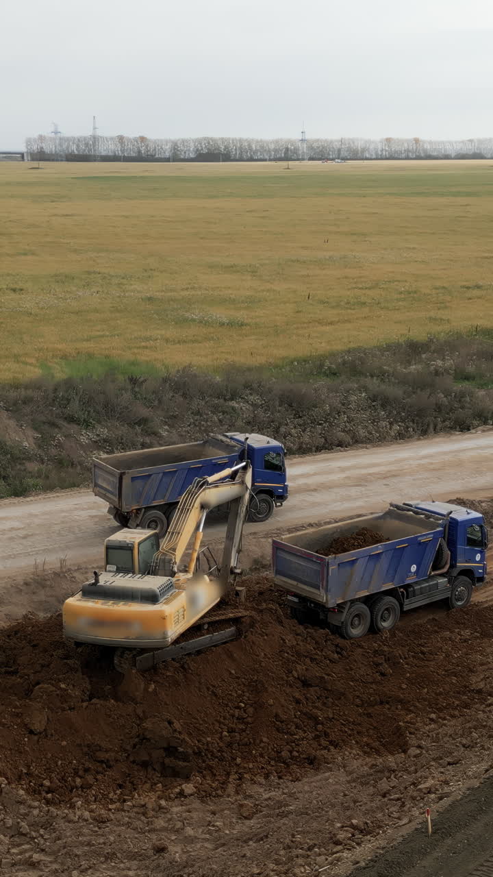 Excavator loading dirt onto dump trucks at a construction site
