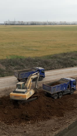 excavator loading dirt onto dump trucks at a construction site