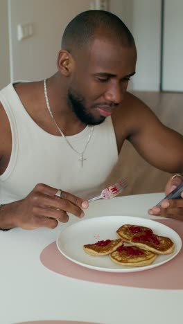 man eating breakfast and looking at phone