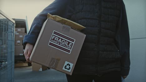 Delivery-man-carrying-a-fragile-package-during-a-delivery-route,-courier-delivering-a-parcel-box