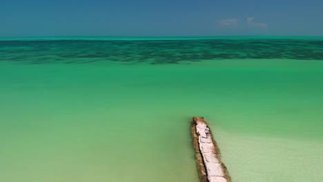 Drohnenansicht-Einer-Person,-Die-Auf-Felsen-Am-Tropischen-Strand-Der-Insel-Holbox-Läuft