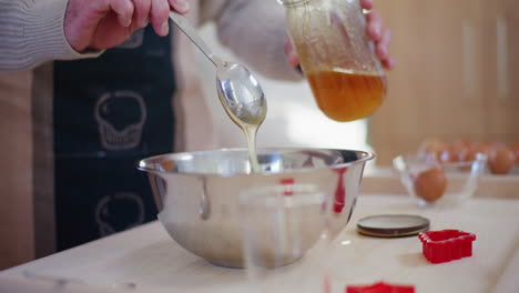 man adds honey to dough while baking holiday pastries