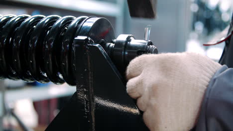 worker fixing black spring during assembly shock absorber at industrial plant