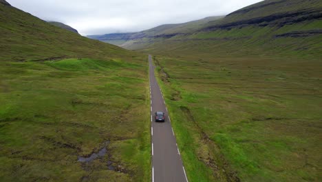 aerial tracking of electric car on remote faroe islands road, cloudy