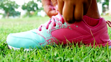 runner is tying up her shoelaces on the grass.