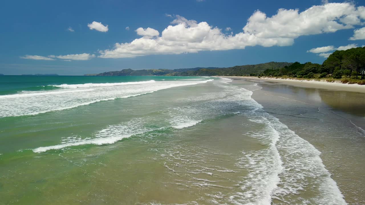 Vuelo aéreo sobre las olas de una playa aislada con marea alta