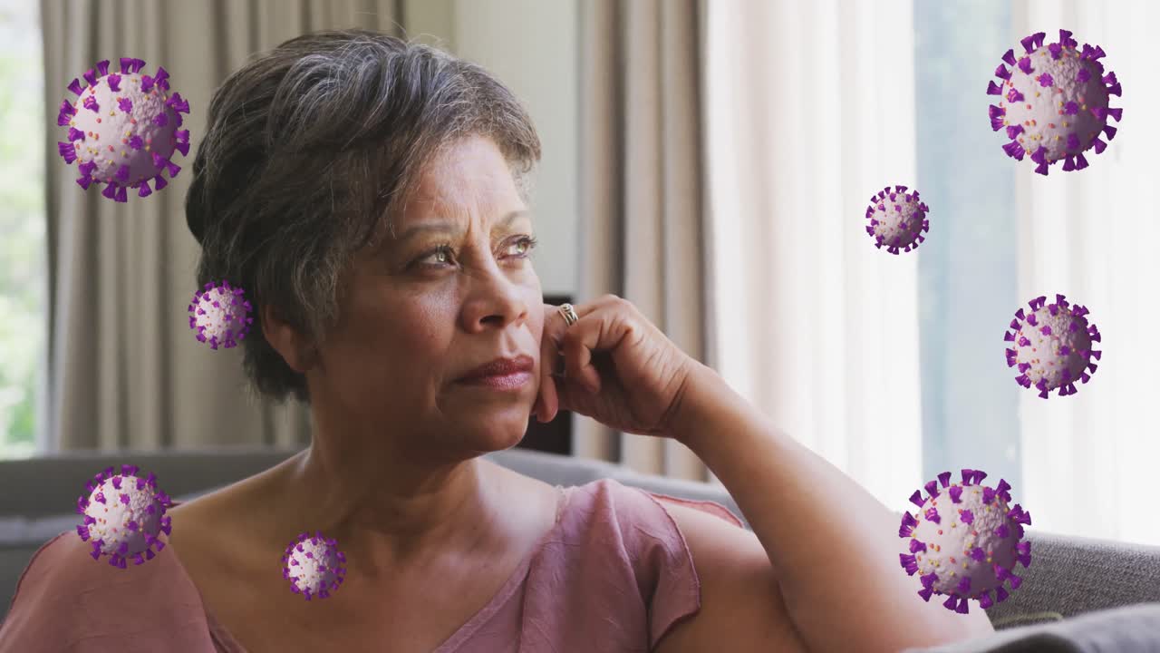 Animation of coronavirus cells rotating over thoughtful senior woman with short hair sitting on sofa