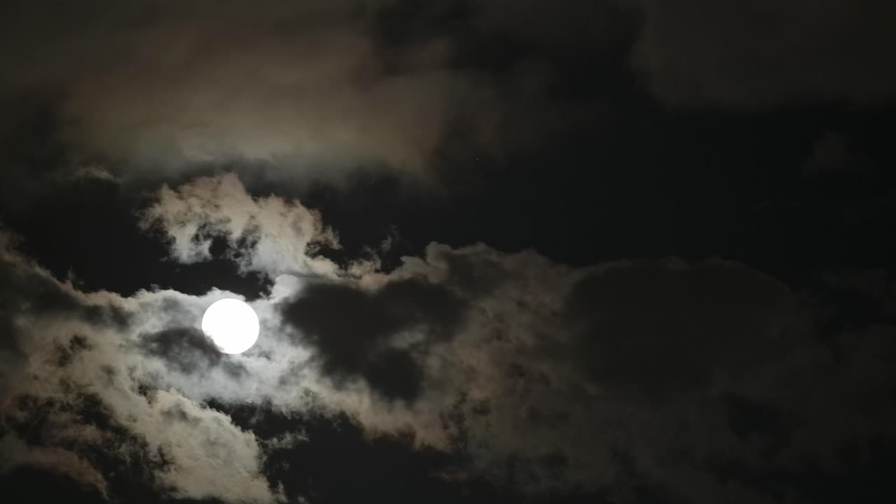 A moon from the dark sky across by the cloud.