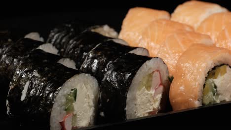 sushi rolls rotates in a plastic container on a black background. meal delivery