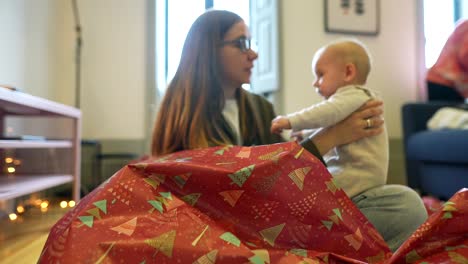 madre y bebé desempaquetando regalos de navidad
