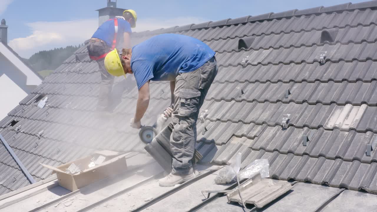 Construction Worker Using Angle Grinder To Cut Tile Standing On Roof. Aerial