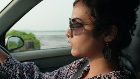 Young-Woman-with-Sunglasses-Paused-at-Red-Traffic-Light-While-Driving