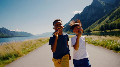 two happy boys running and laughing on a scenic path by a lake and mountains