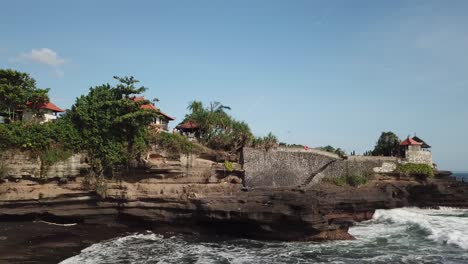 ocean waves crashing against a cliffside temple in bali