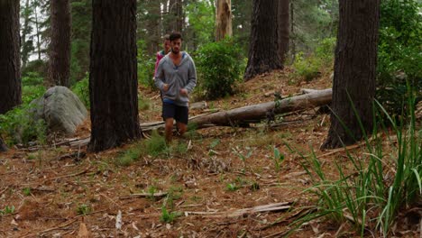 couple jumping over a tree trunk