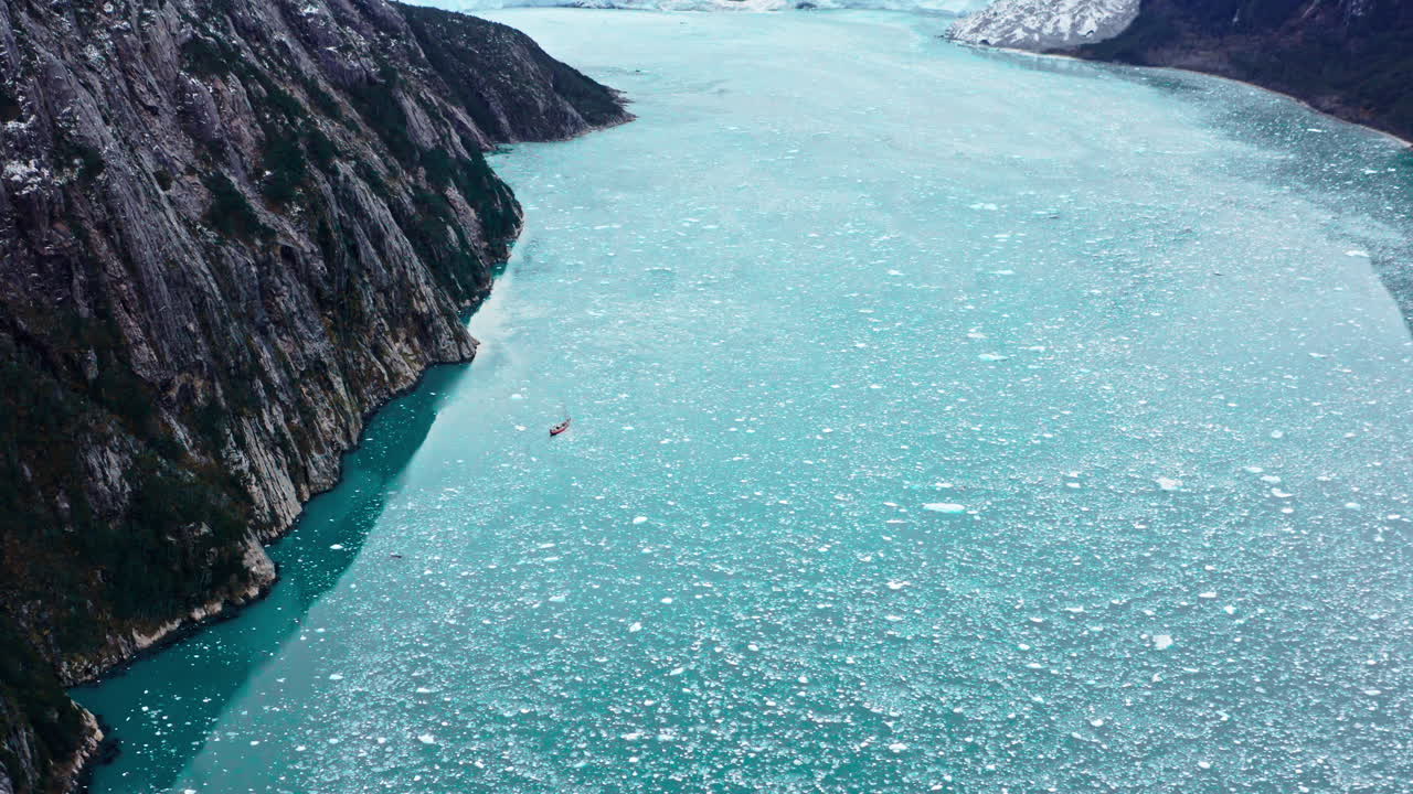 Boat Sailing On The Water With Floating Ice Fragments Near Cape Horn In Chile. Aerial Drone Shot