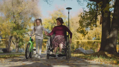 Liebevolle-Mutter-Und-Kleine-Tochter-Mit-Langen-Zöpfen-Gehen-Im-Park-Spazieren