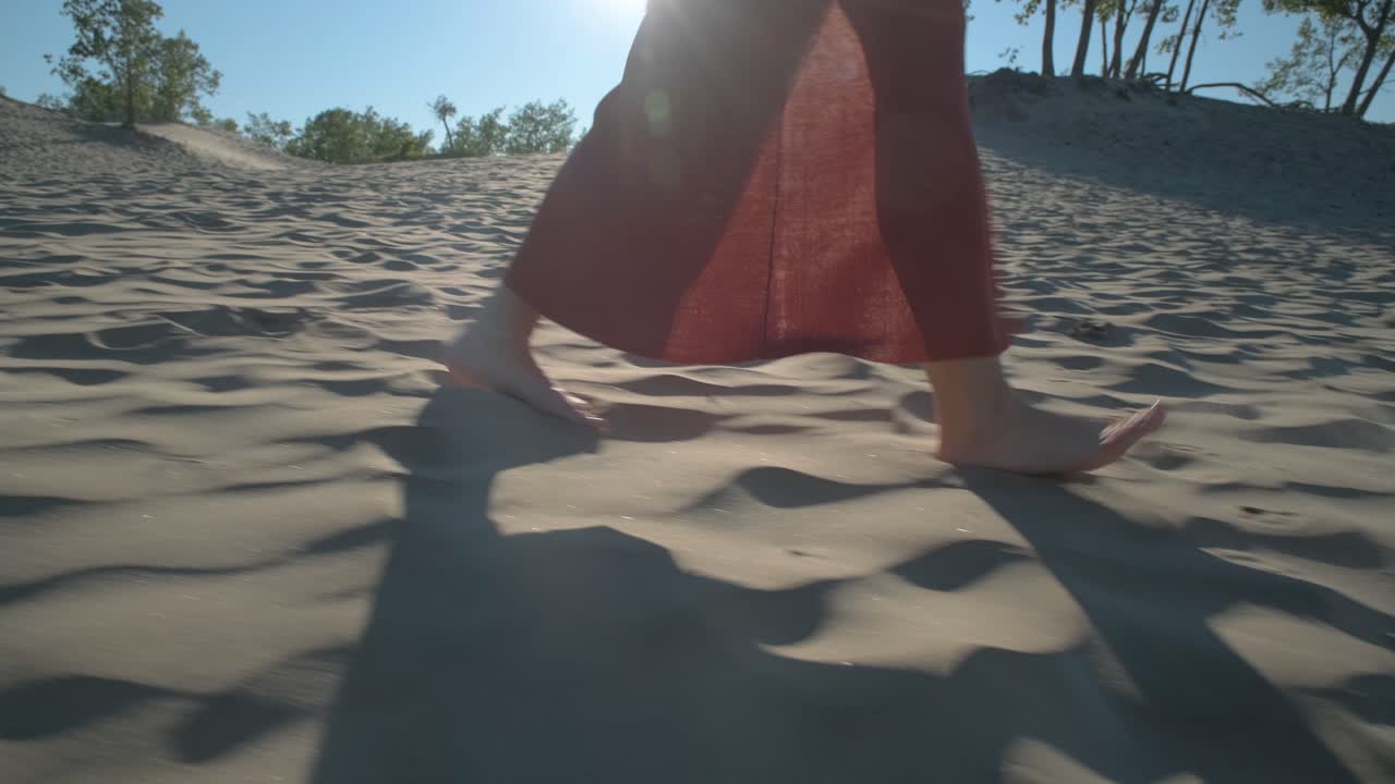 Woman walking barefoot towards the camera in the sand dunes of Sandbanks