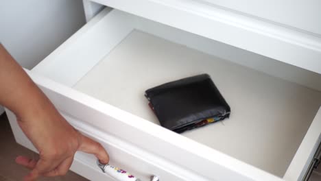 person opening a drawer, and a wallet inside