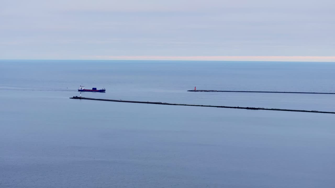 Aerial panorama reveals cargo vessel crossing sea gate into Riga harbor, Europe