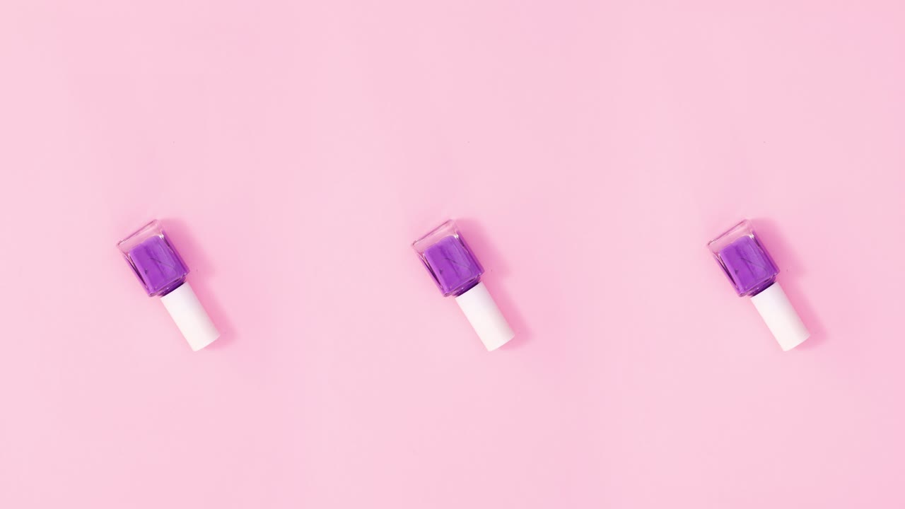tres botellas de esmalte de uñas giran sobre un fondo rosa pastel. detenga el movimiento