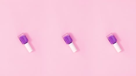tres botellas de esmalte de uñas giran sobre un fondo rosa pastel. detenga el movimiento