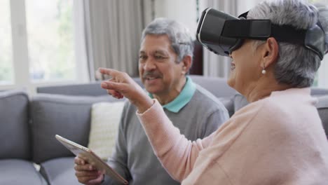 happy mixed race senior couple wearing vr headset and having fun at home