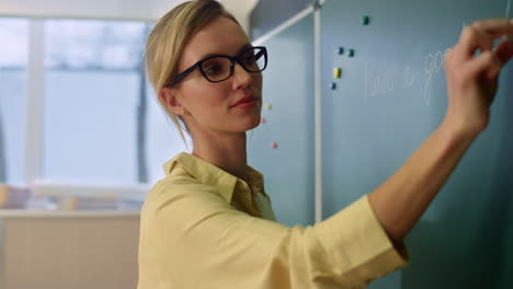 Teacher-writing-on-blackboard.-Schoolteacher-explaining-lesson-in-classroom