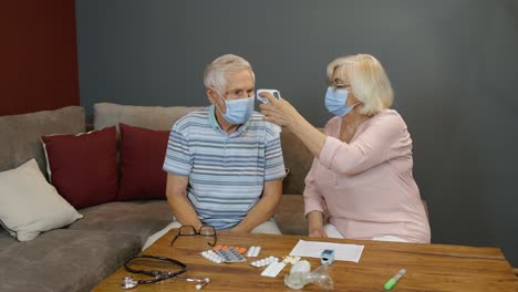 Pareja-De-Ancianos-Mide-La-Temperatura-Con-Un-Termómetro-Digital-Sin-Contacto-Durante-El-Bloqueo-Del-Coronavirus